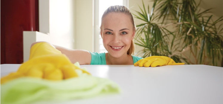 a female cleaner cleaning a table with a smile on her face