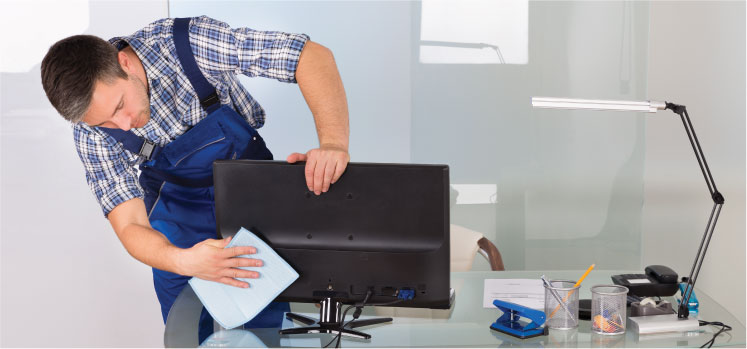 a cleaner cleaning a computer monitor at an office