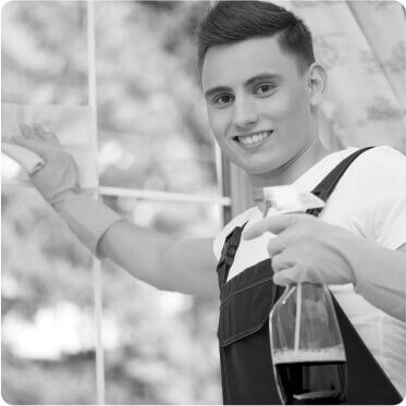 a cleaner smiling at the camera while cleaning a dirty window